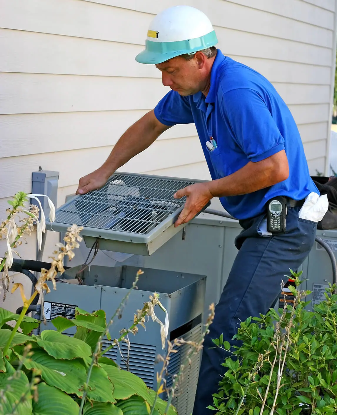 Technician repairing outdoor air conditioning unit.